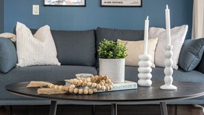 Une table ronde ornée d’un livre, d’une plante en pot et de deux chandeliers.