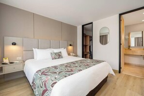 Une chambre d’hôtel moderne avec un grand lit, des tables de chevet, un miroir et une armoire.