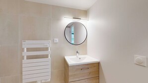 Un bagno moderno con lavandino bianco, uno specchio e un porta asciugamani.