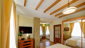 A bedroom with a large bed, a wooden dresser, a stone pillar, a television, and a view into another room. - Zaivan Retreat (Breaza de Jos)