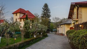 A stone pathway leading to a building with a red roof, surrounded by well-maintained hedges and trees. - Zaivan Retreat (Breaza de Jos)