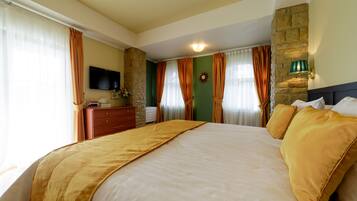 Una habitación de hotel con una cama grande, un aparador, un televisor de pantalla plana y una pared decorativa de piedra.