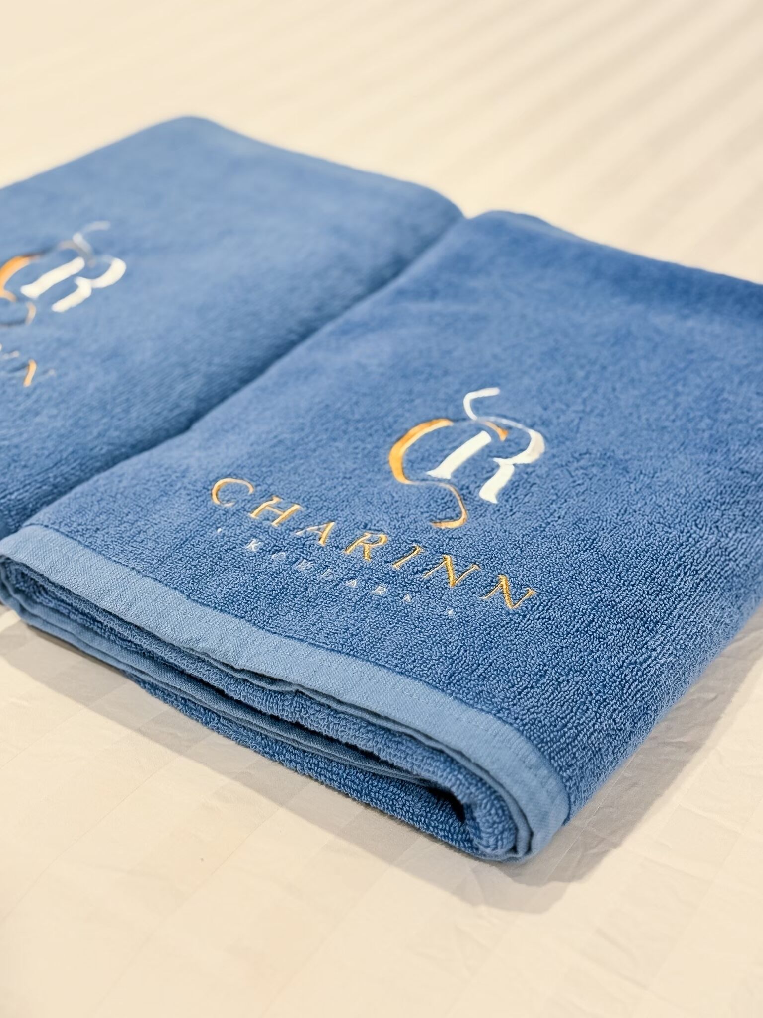 A folded blue towel with embroidered text and a logo.