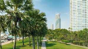A pathway lined with palm trees, leading to a body of water with boats.