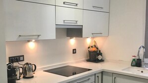 Een moderne keuken met witte kastjes, een zwart aanrecht en een inbouwoven.