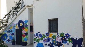 Un edificio con murales coloridos de flores, un delfín y una escalera.