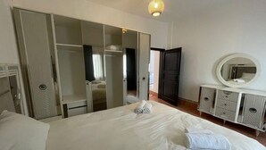 Un dormitorio con una cama grande, un armario, un tocador y un espejo.