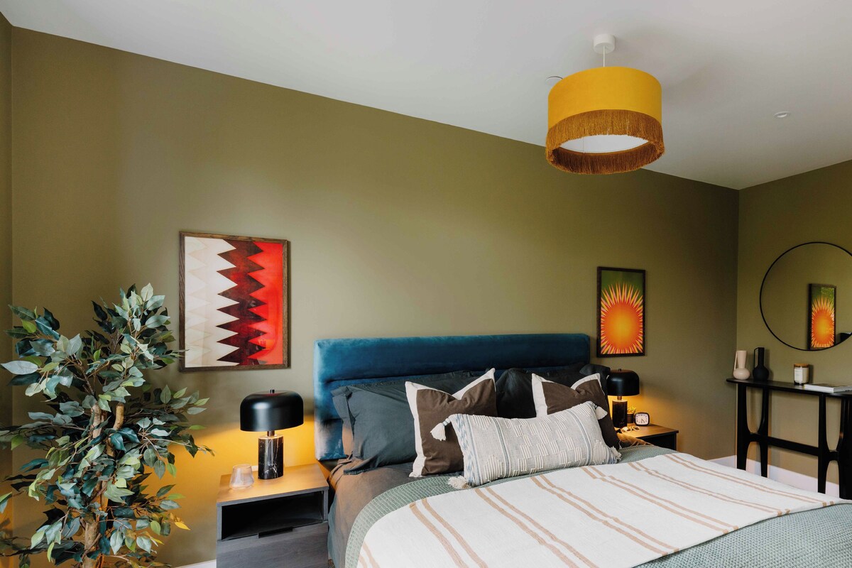 A bedroom with a bed, nightstands, a lamp, a mirror, and wall art.