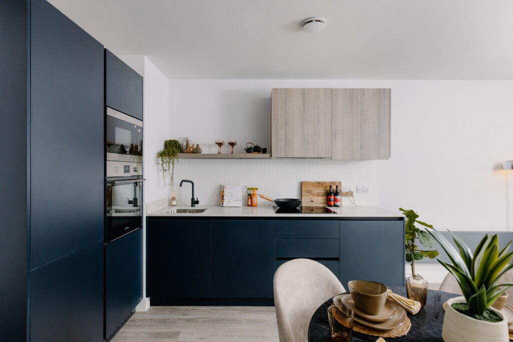 Una cocina moderna con armarios oscuros, encimera de madera y un diseño minimalista.