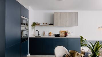 Ett modernt kök med mörka skåp, en bänkskiva i trä och en minimalistisk design.
