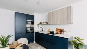 Una cocina moderna con armarios azul oscuro, encimera blanca y salpicadero de madera.
