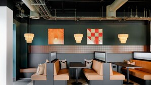 Un restaurante moderno con asientos tipo cabina y mesas, iluminación colgante y obras de arte en la pared.