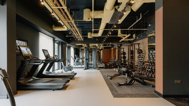 Un gimnasio con cintas de correr, máquinas de pesas y una variedad de equipos de ejercicio.
