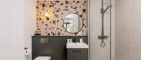 A modern bathroom with a toilet, sink, and shower.