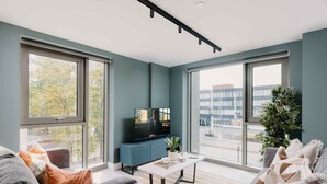 Una sala de estar moderna con televisor, una mesa de centro y un ventanal con vistas a la ciudad.