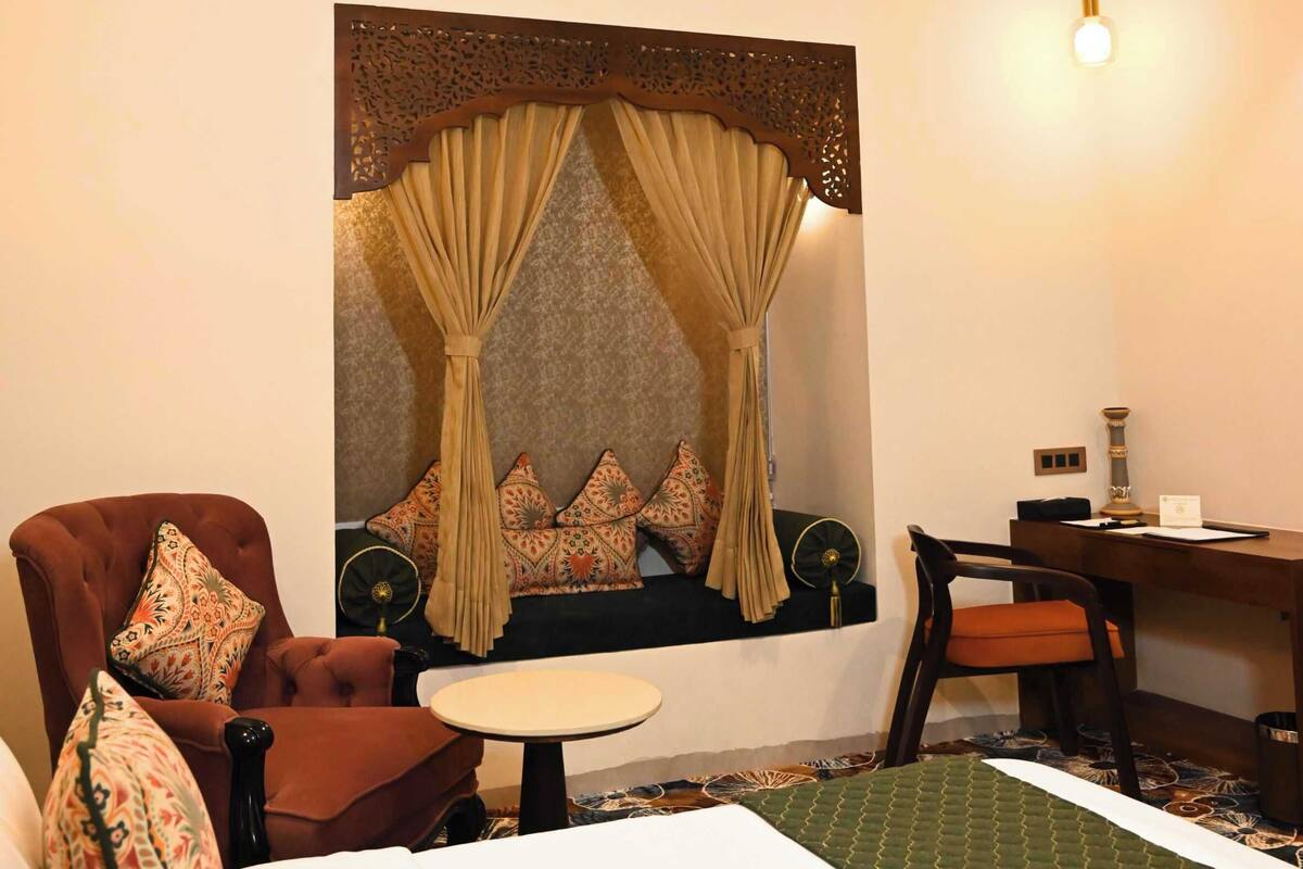 A hotel room with a bed, a sofa, a desk, and a chair.