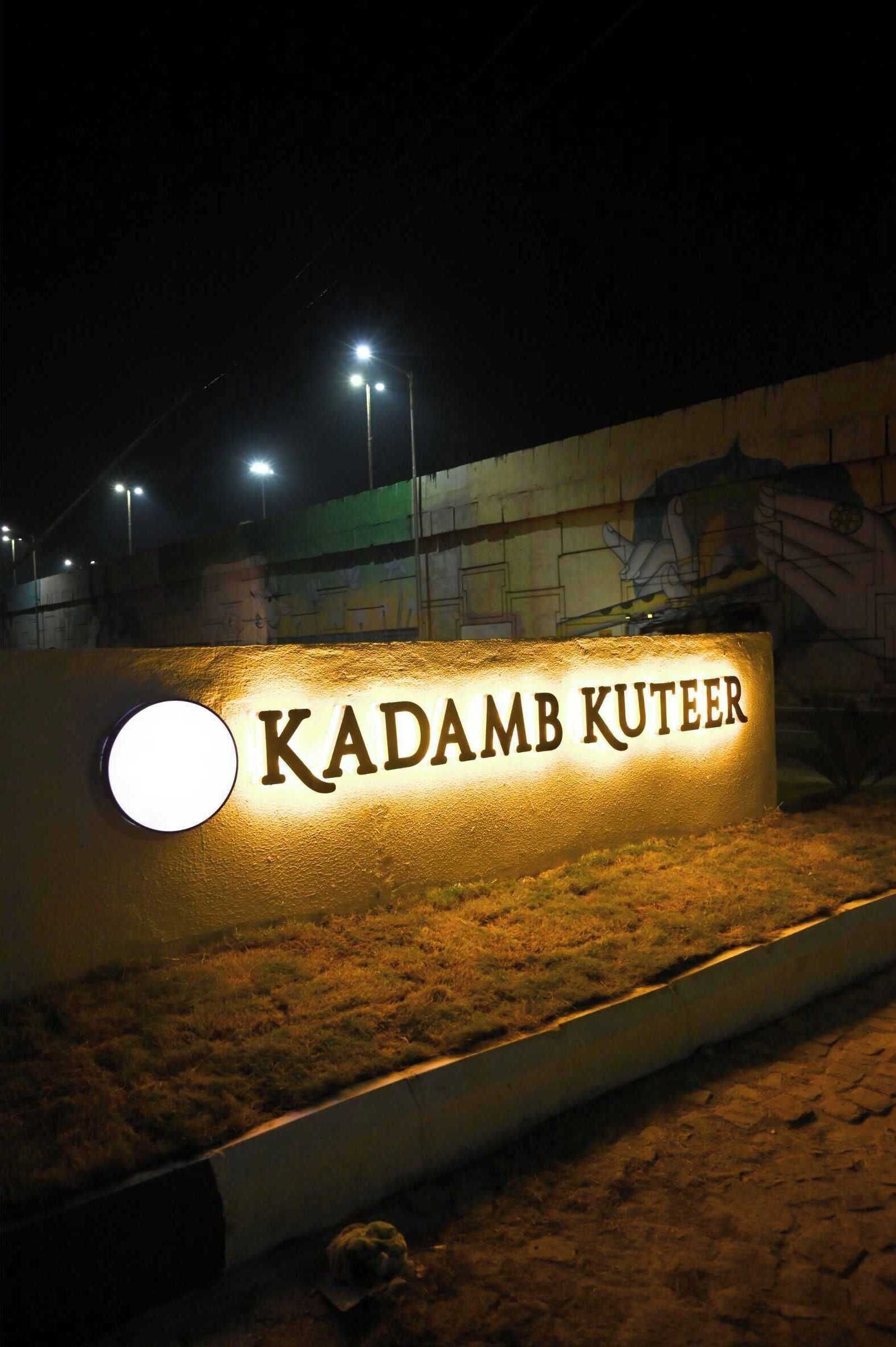Ein Schild mit der beleuchteten Aufschrift 'KADAMB KUTEER' in der Nacht.
