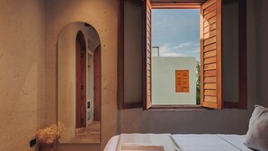 A bedroom with a bed, a window with wooden shutters, a mirror, and a view of a building outside. - Casa del Espiritu Santo - La Santisima Cartagena (Unknown)