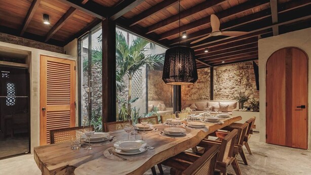 A long wooden dining table set for a meal, with chairs on both sides. - Casa del Espiritu Santo - La Santisima Cartagena (Unknown)