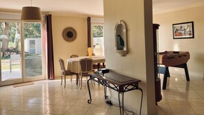 A dining area with a table, chairs, a lamp, and a foosball table.