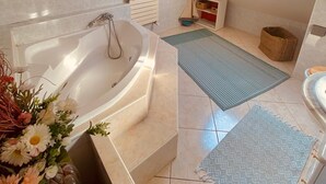 A modern bathroom with a freestanding bathtub, a skylight, and a small window.