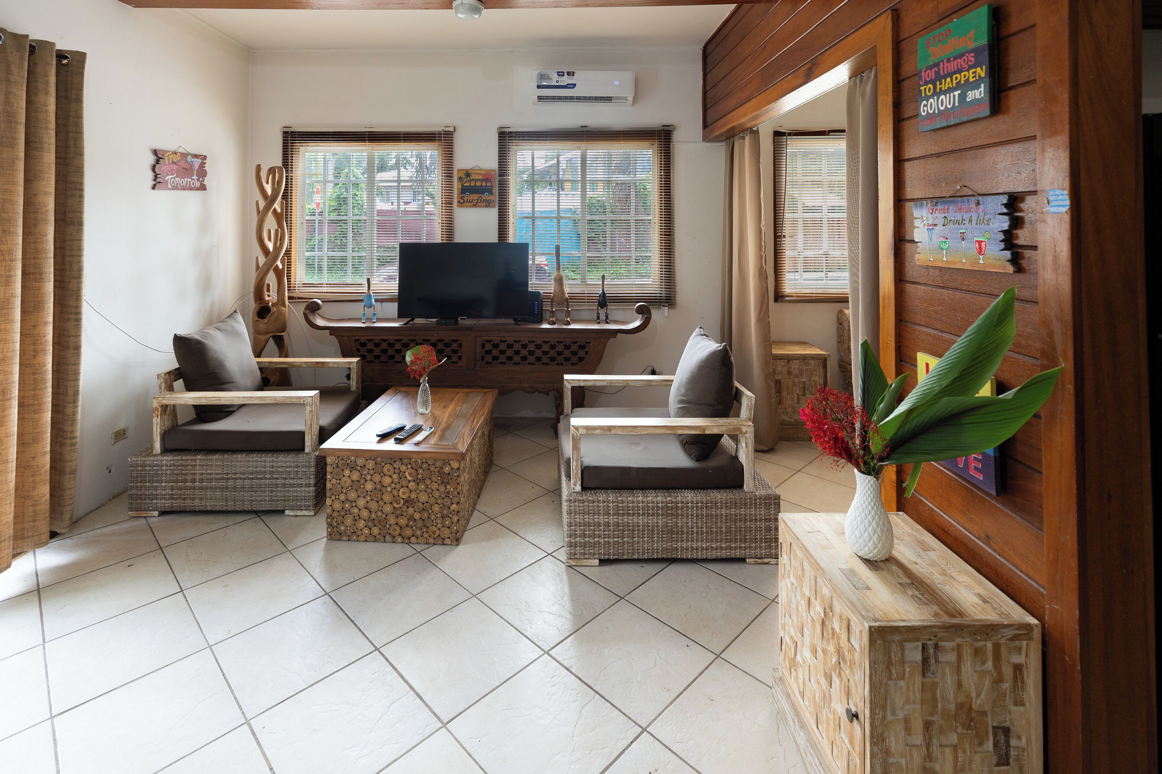 A living room with a television, two sofas, a coffee table, and a decorative wall with signs.
