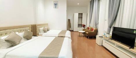 Habitación de hotel con dos camas, televisor, sofá y una mesita.
