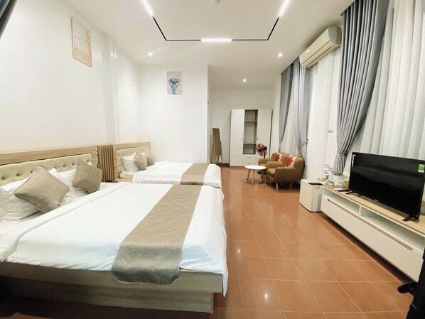 Habitación de hotel con dos camas, televisor, sofá y una mesita.
