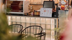 A coffee shop interior with a modern espresso machine, a menu stand, and a decorative cat figure. - Gaki Hotel (Hue)