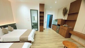 A hotel room with two beds, a small table, wooden cabinets, and a kitchenette. - Gaki Hotel (Hue)
