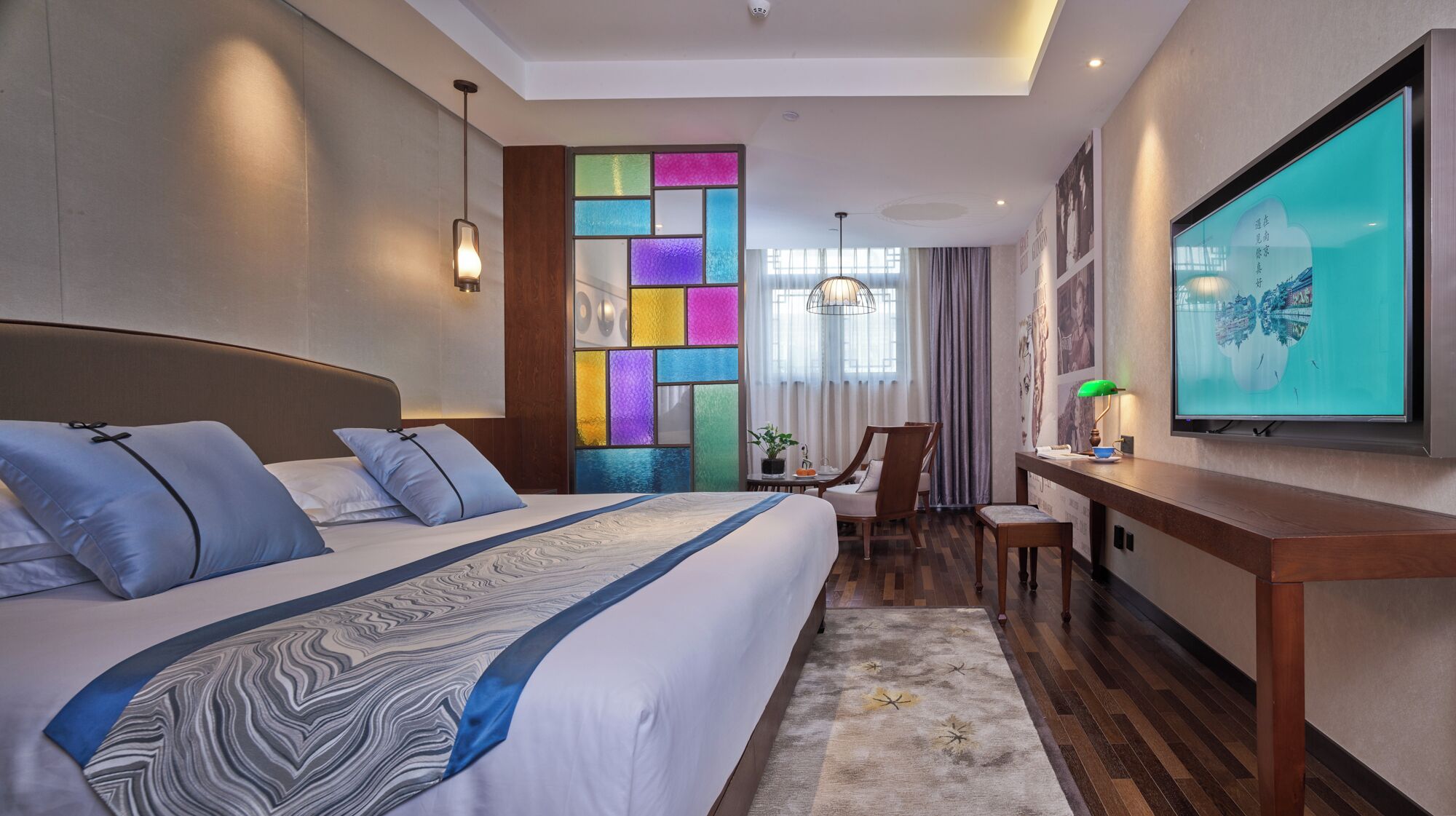Ein modernes Hotelzimmer mit einem großen Bett, einem Schreibtisch und einem Flachbildfernseher sowie einer farbenfrohen Wandverkleidung.