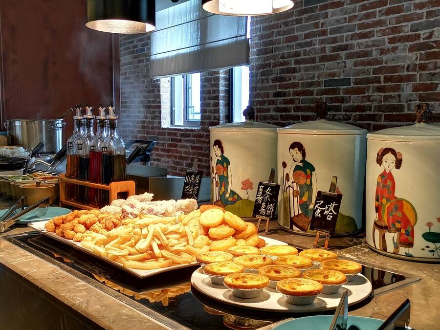 A buffet with various dishes, including French fries, pastries, and a selection of sauces.