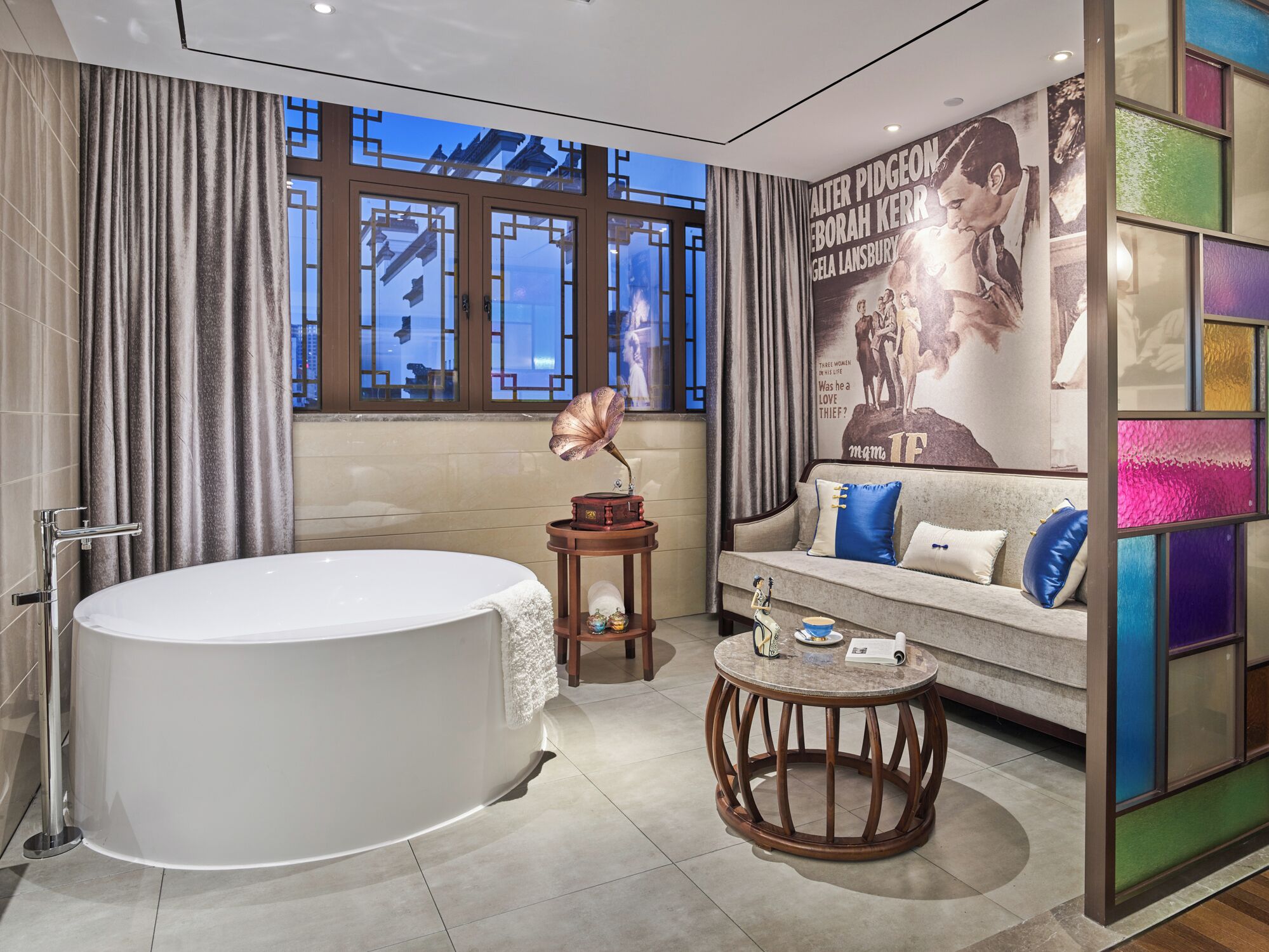Un baño moderno con una bañera independiente, un tocador con espejo y un gramófono decorativo.