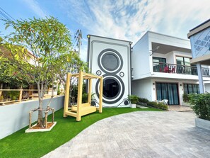 A modern building with a unique circular design, a well-maintained lawn, and a paved walkway. - Amiigo Kohlarn (Koh Lan)