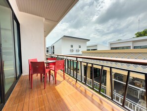 A balcony with wooden flooring, red chairs, and a glass door. - Amiigo Kohlarn (Koh Lan)
