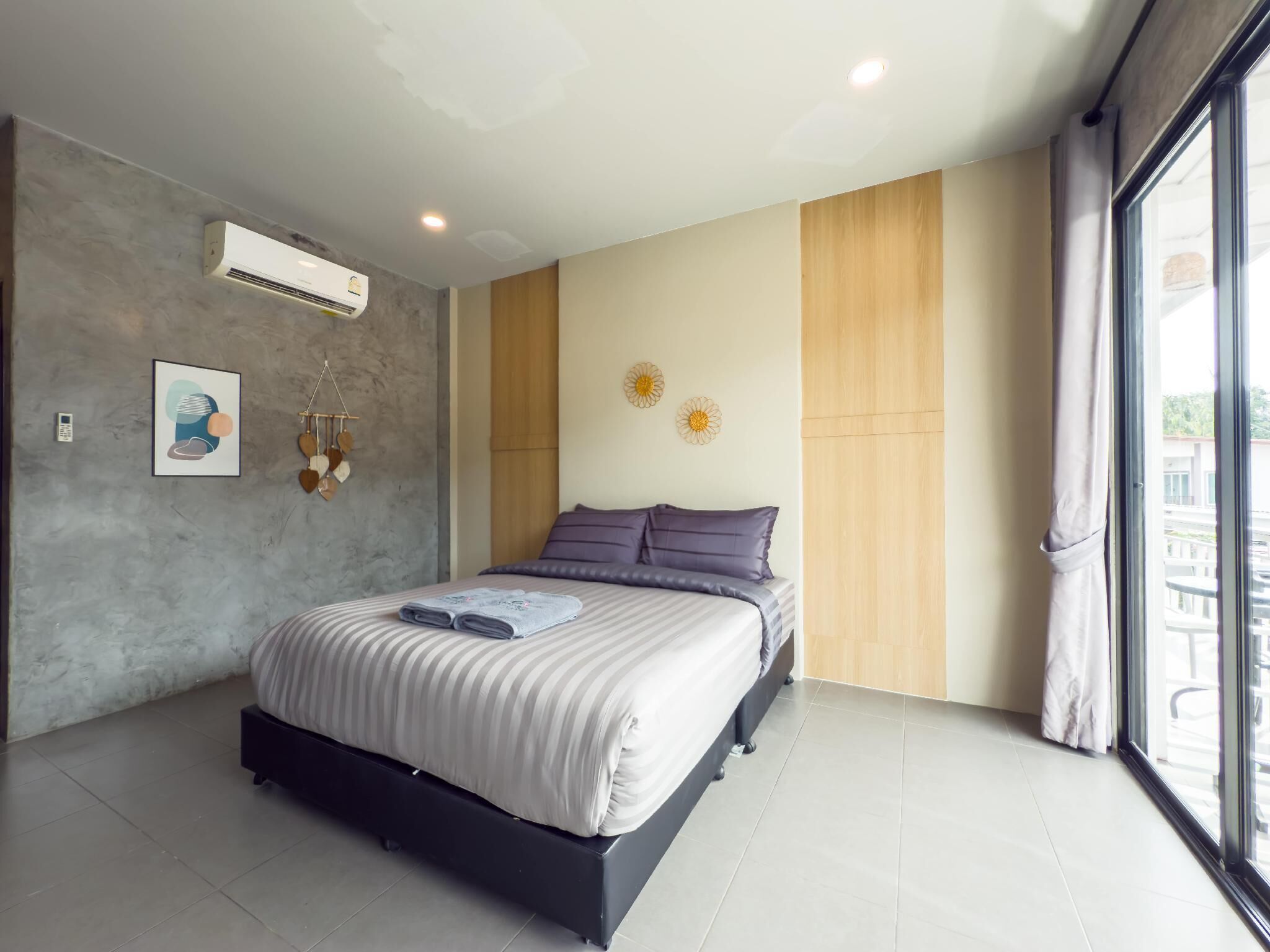 Un dormitorio moderno con una cama grande, aire acondicionado integrado y vistas al exterior a través de un amplio ventanal.