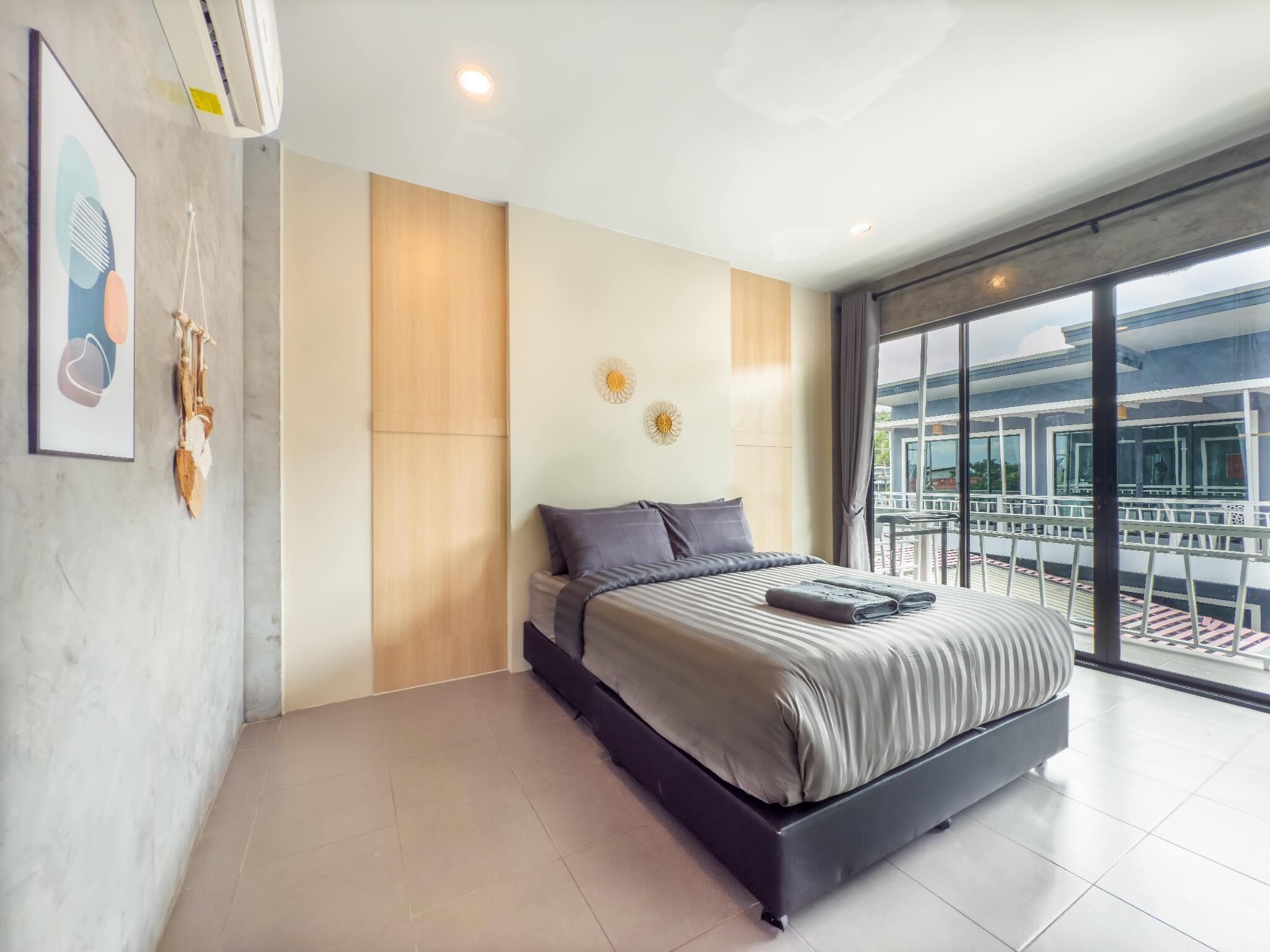 A modern bedroom with a large bed, a view of the outside balcony, and a ceiling fan.