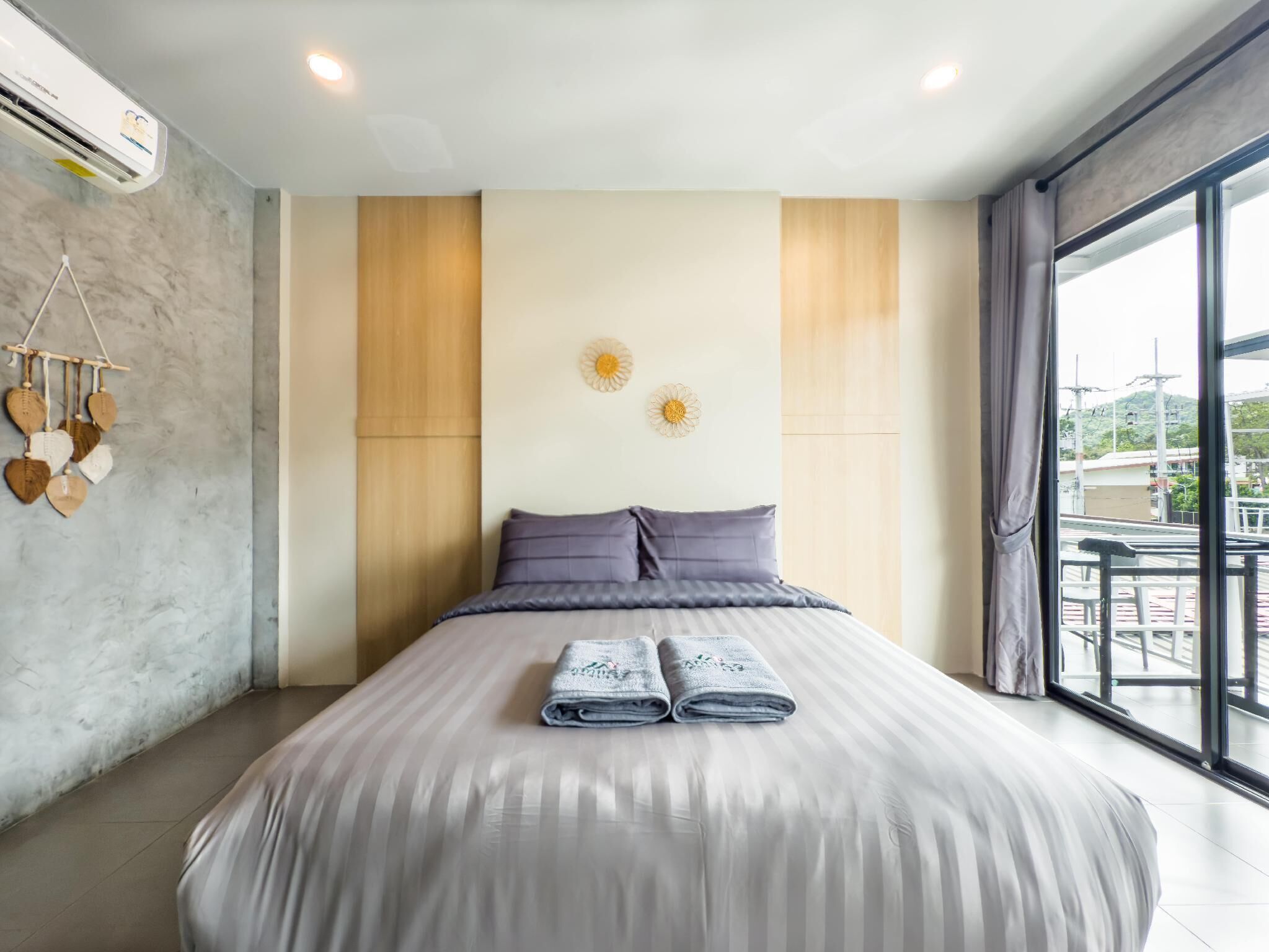 A modern hotel room with a large bed, a view of the city, and a decorative wall hanging.