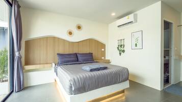 A modern bedroom with a large bed, wooden headboard, and a view of the outdoors.
