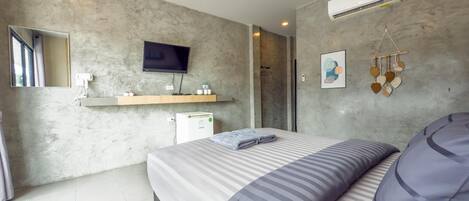 A modern bedroom with a bed, a mounted TV, a small refrigerator, and a wall-mounted air conditioner.