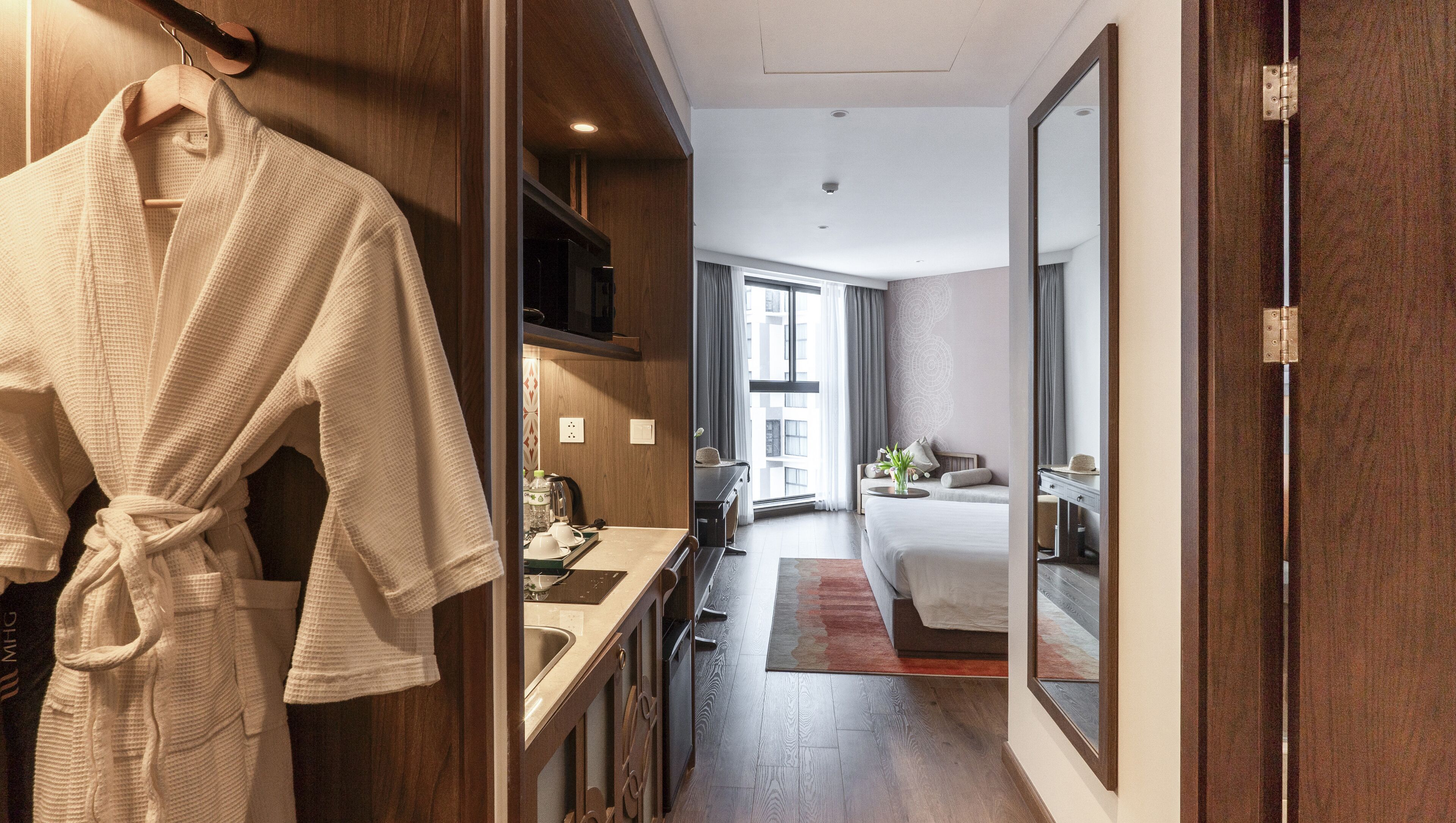 Une chambre d’hôtel avec une armoire en bois, une salle de bain avec un lavabo et un lit donnant sur la ville.