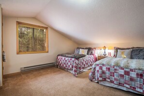A bedroom with two beds, a window with blinds, a heater, and a bedside lamp. - Conchas Cabin by Velo (Angel Fire)