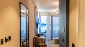Un couloir d’hôtel avec un grand miroir, un espace repas avec des chaises et une vue sur la mer.