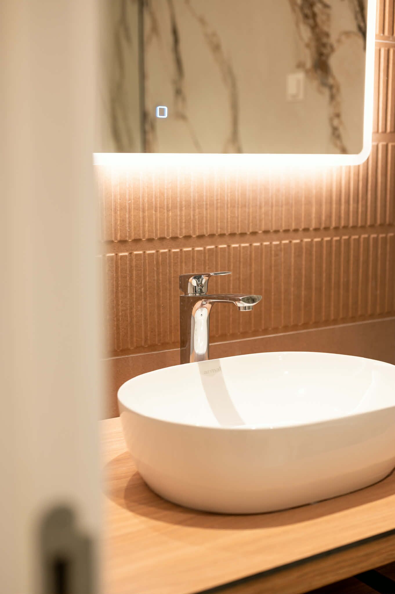 A bathroom with a white sink, a mirror, and a wooden vanity.