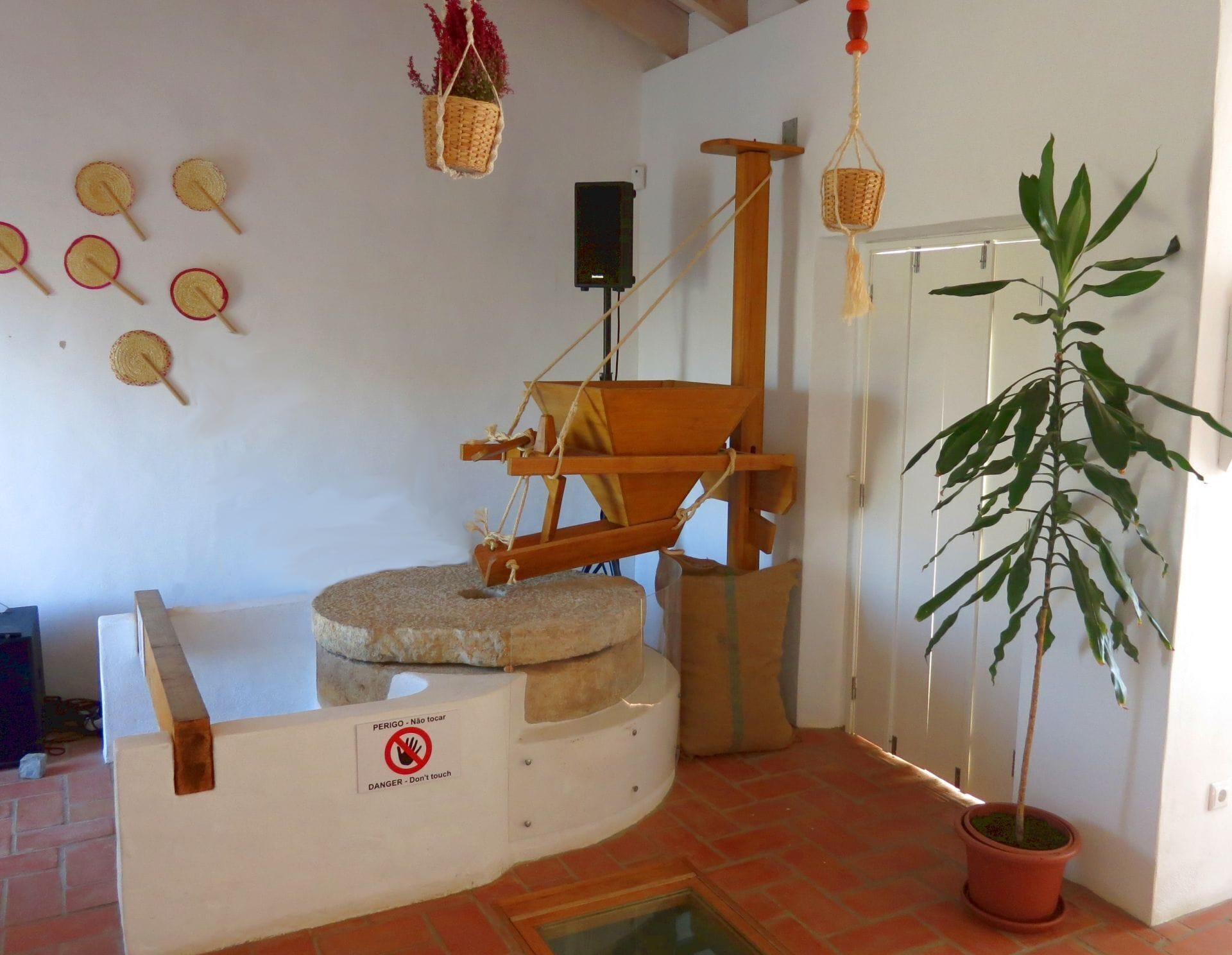 Une pièce comprenant un rouet traditionnel, un panneau d’avertissement et une plante en pot.