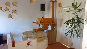 A room with a traditional spinning wheel, a warning sign, and a potted plant.