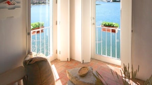 A room with a view of the sea through open doors, a tiled floor, and a potted plant. - Moinho das Marés (Olhao)