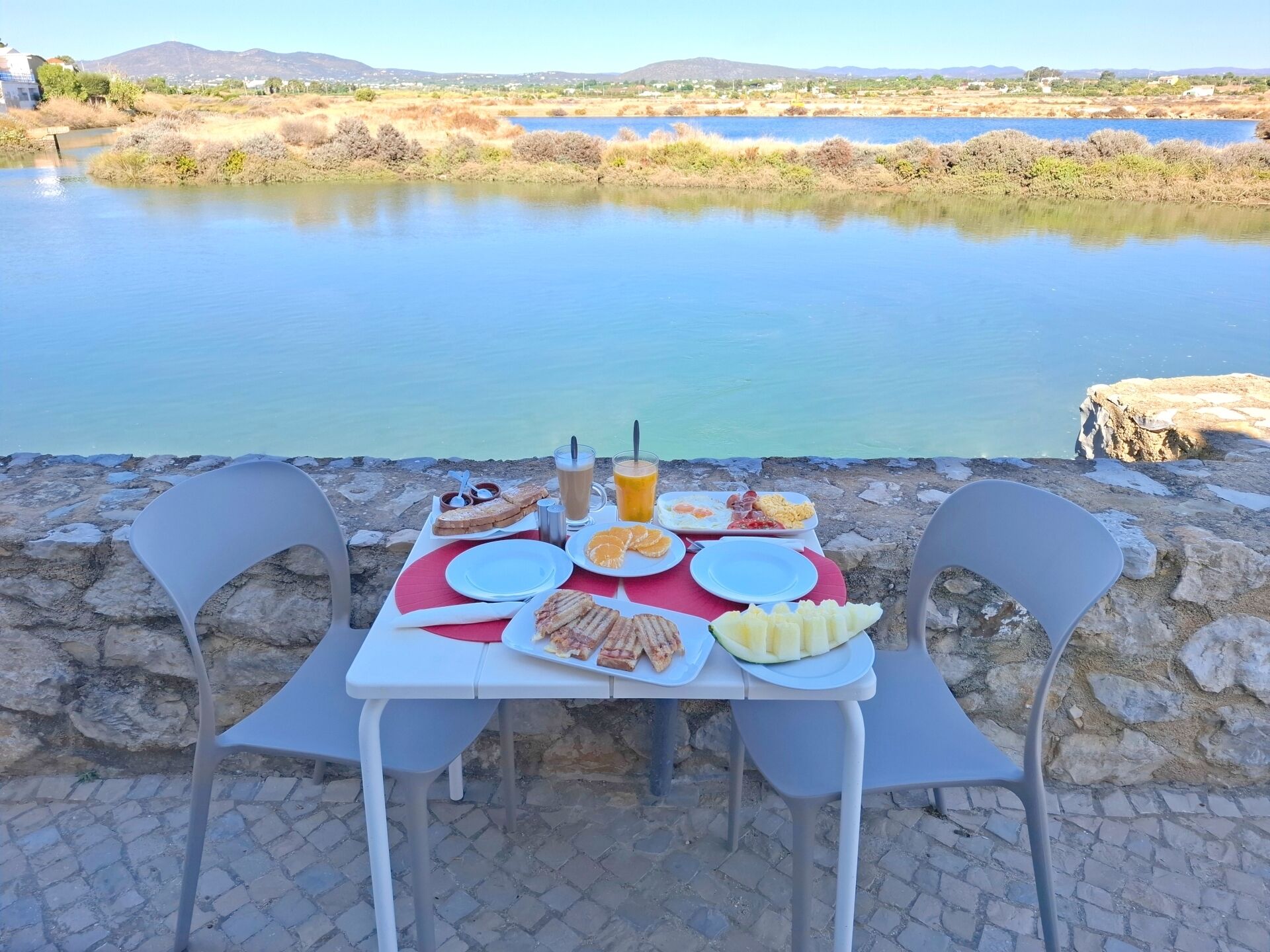 Une table dressée avec des aliments pour le petit-déjeuner, donnant sur un lac.