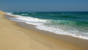 A beach with a sandy shore and waves approaching the beach. - Moinho das Marés (Olhao)