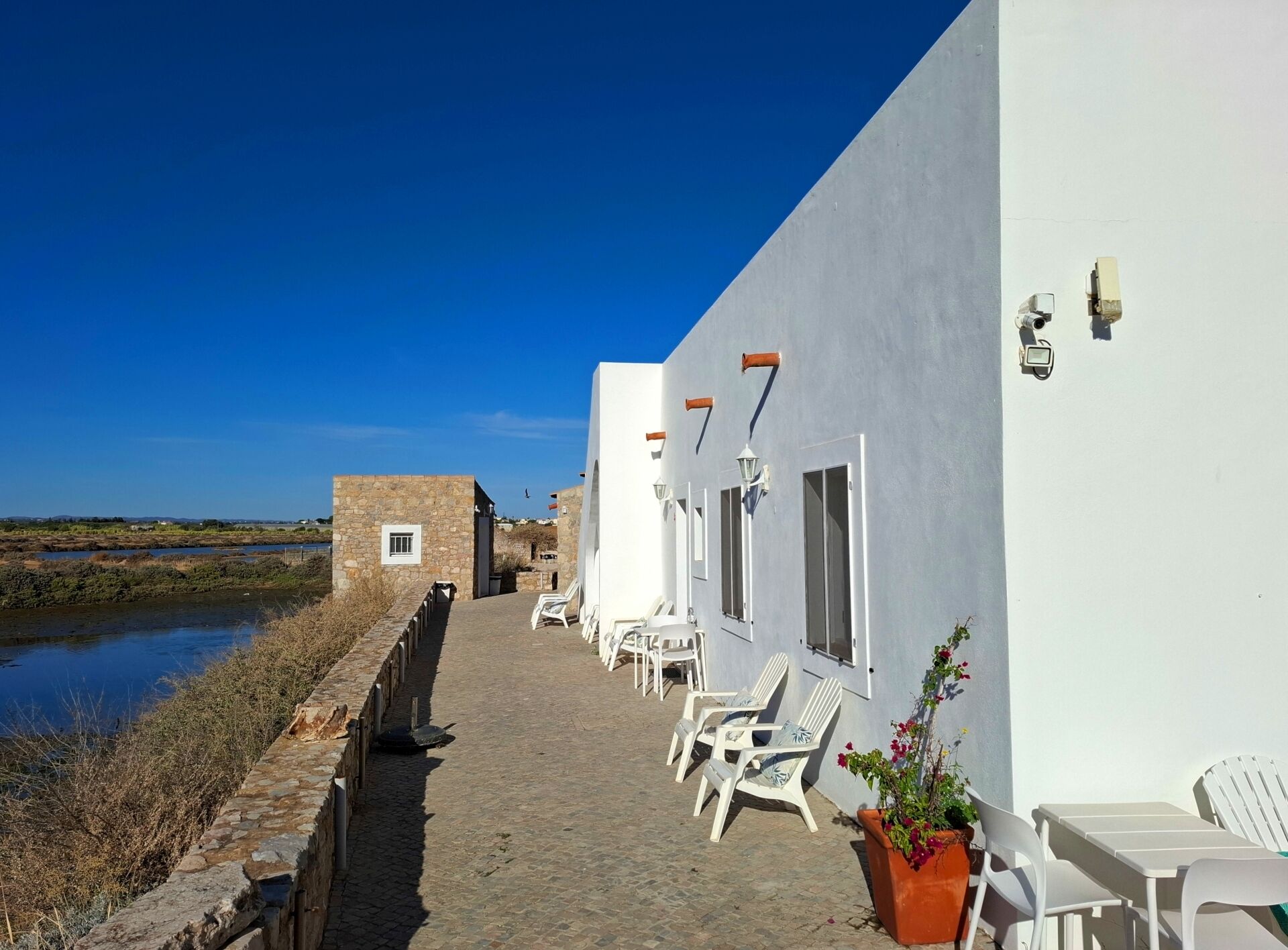 A coastal building with a stone pathway leading to outdoor seating.
